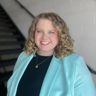 Headshot of Taylor Koon, blond woman in a blue jacket