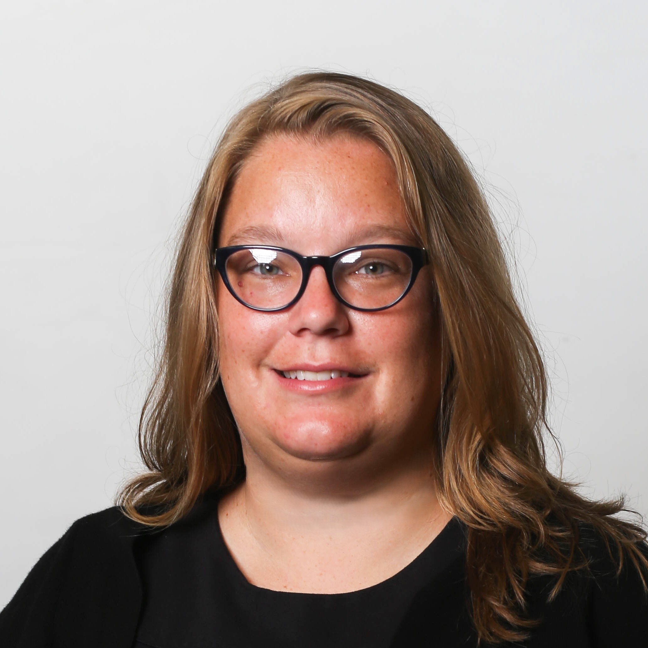 Headshot of a blonde woman with glasses dressed in black.