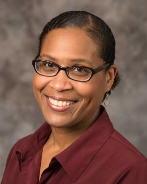 Picture of a woman in glasses wearing a reddish brown collared shirt